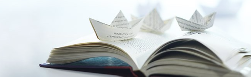 a paper boat on an open book