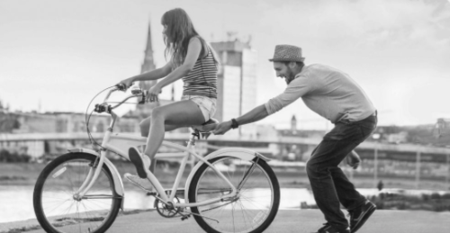 a man pushing a woman on a bicycle
