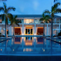 a pool with palm trees and a building with a white wall