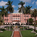 a pink building with palm trees with Boca Raton Resort in the background