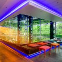 a pool with a glass wall and chairs