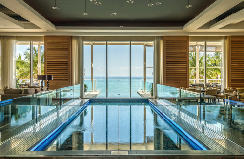 a pool inside a room with a view of the ocean