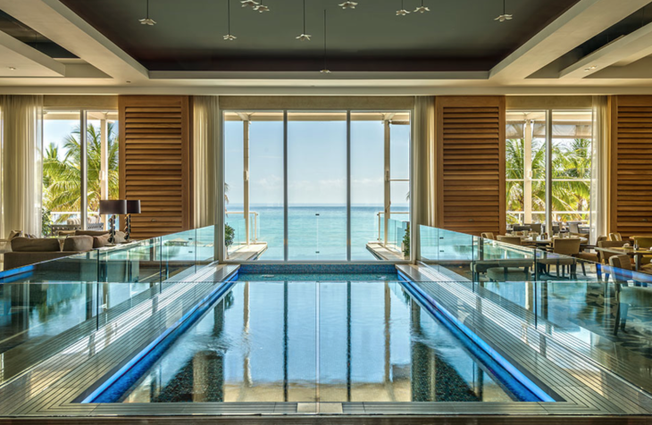 a pool inside a room with a large window overlooking the ocean