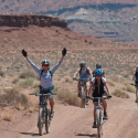 a group of people riding bikes on a dirt road