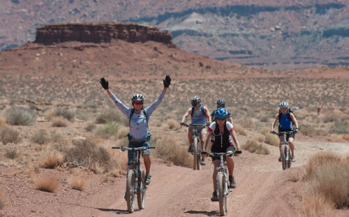 a group of people riding bikes on a dirt road