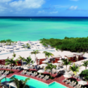 a pool and beach with umbrellas and chairs