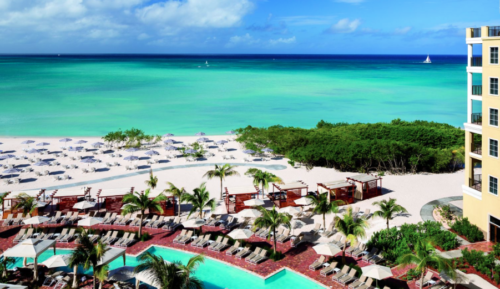 a pool and beach with umbrellas and chairs