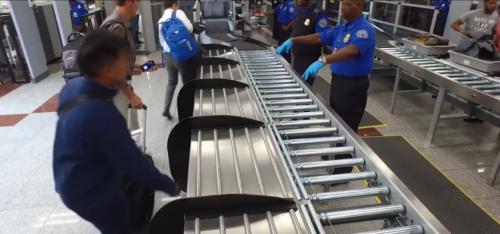 a group of people standing next to a conveyor belt