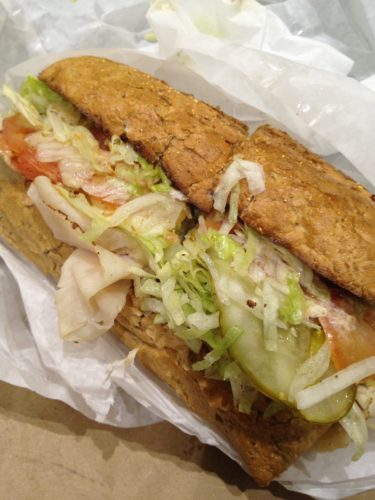 a sandwich with meat and vegetables on a white paper