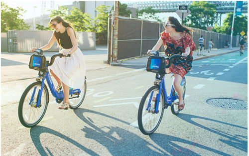 two women riding bicycles on a street