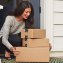 a woman holding boxes in front of a door
