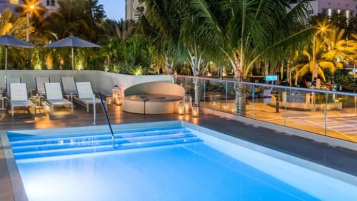 a pool with a deck and palm trees