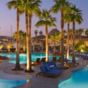 a pool with palm trees and lounge chairs