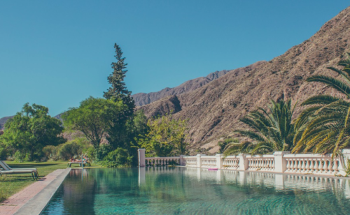 a pool with trees and mountains in the background