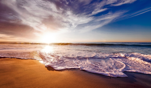 a beach with waves and a blue sky