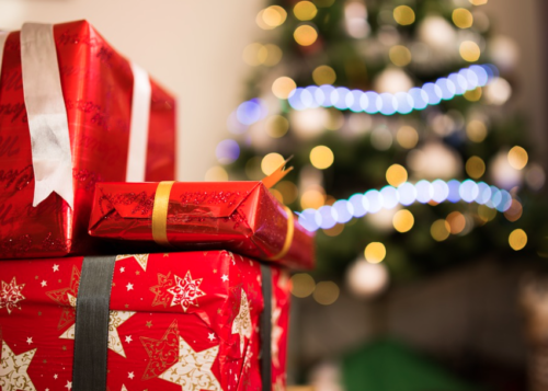 a stack of presents in front of a christmas tree