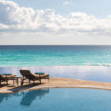 a pool with chairs and a body of water