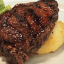 a piece of meat with potatoes and vegetables on a white plate