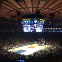 a basketball game in a stadium with Madison Square Garden in the background