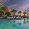 a pool with palm trees and a building