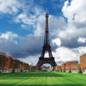 a tall metal tower with trees and grass in front of it