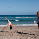 a boy doing a cartwheel on a beach