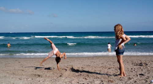 a boy doing a cartwheel on a beach