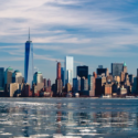 a city skyline with water and clouds in the sky