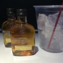 two bottles of alcohol next to a cup of ice