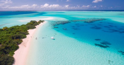 a beach with boats and blue water