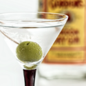 a martini glass with a green olive in it