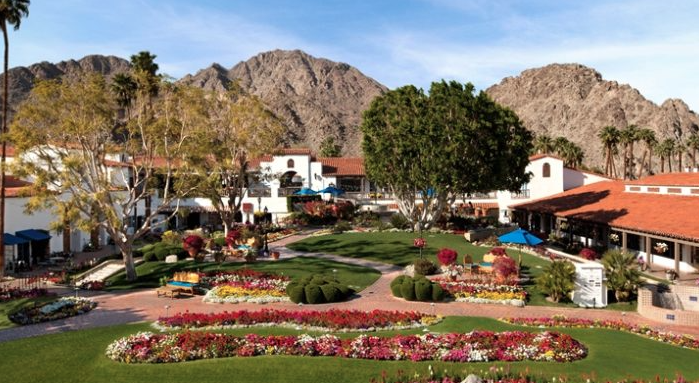 a garden with flowers and trees in front of a building