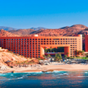 a large building with a beach and mountains in the background