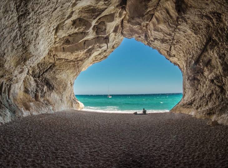 a cave with a beach and water in the background