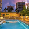 a pool with chairs and trees in front of buildings