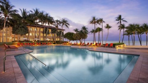 a pool with palm trees and a building