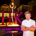 a man in a white coat standing in front of a large purple sign