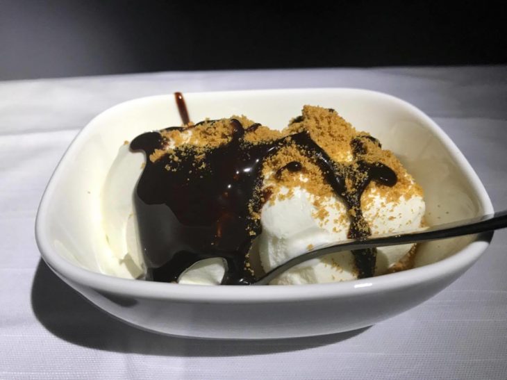 a bowl of ice cream with chocolate sauce and brown crumbles