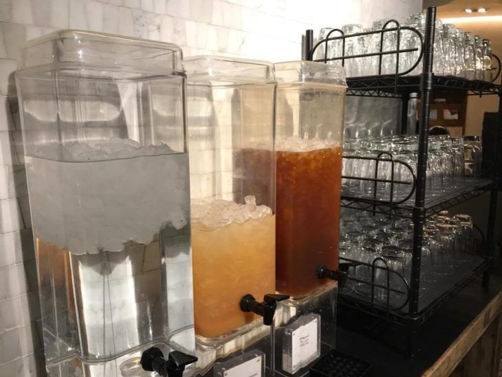 a group of water dispensers with ice and liquid in them