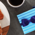 a blue gift box with a bow tie next to a cup of coffee