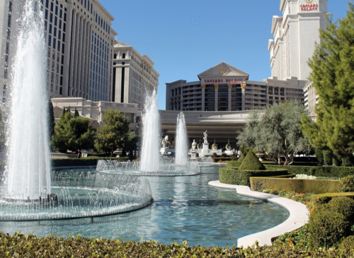 a water fountains in front of a large building with Caesars Palace in the background