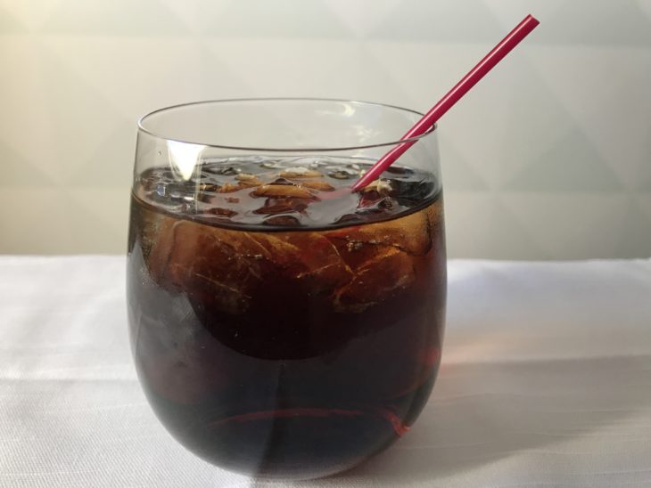 a glass of brown liquid with a straw