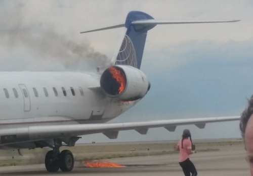 a woman walking on a runway with a jet engine on fire