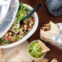 a bowl of salad and burrito next to a burrito