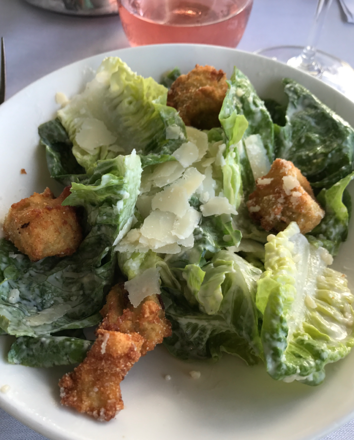 a plate of salad with croutons and parmesan cheese