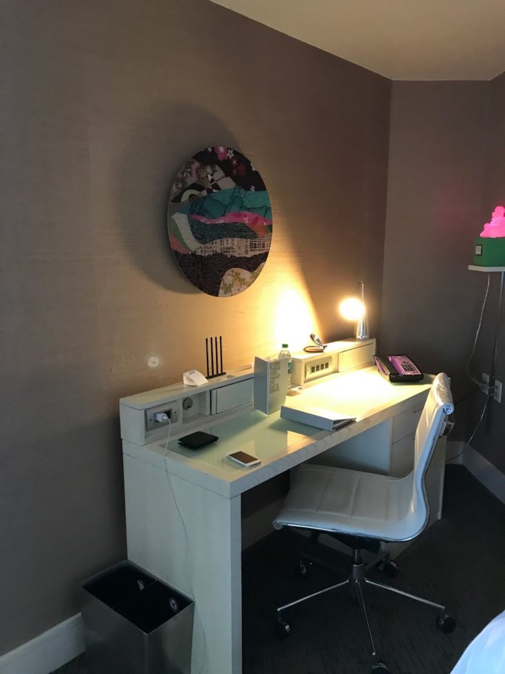 a desk with a chair and a lamp on the wall