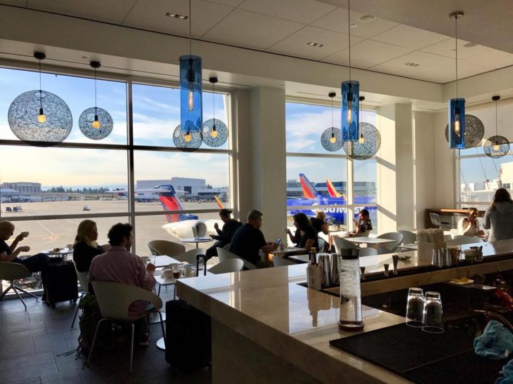 people sitting at tables in a room with airplanes in the background