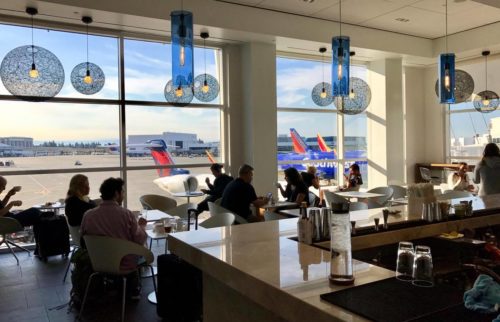 people sitting at tables in a room with airplanes in the background