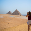 a woman taking a picture of pyramids