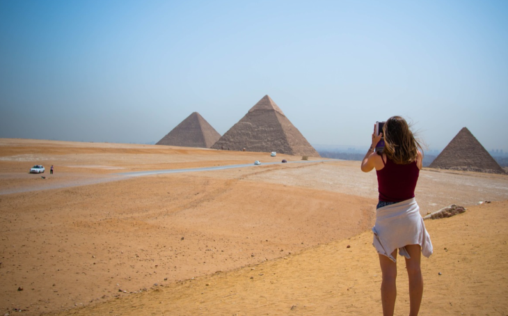 a woman taking a picture of pyramids